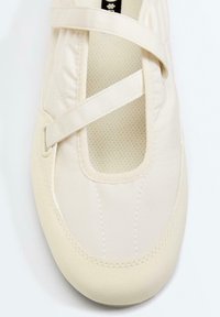 Chaussure style Mary Jane beige clair avec brides croisées et insert en tissu texturé sur le dessus vue de dessus.