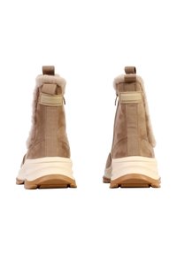 Bottines en daim tan avec doublure pelucheuse, accents beige contrastants, et une semelle blanche coussinée. Comprend des panneaux élastiques sur les côtés et des languettes de tirage.