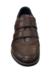 Bruine leren schoen met drie klittenbandsluitingen, ronde neus en contrasterende zwarte accenten op de kraag en zool. Vlotte textuur.