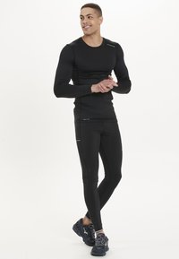 Svart långärmad träningströja och åtsittande leggings med en mjuk, elastisk textur. Utsmyckad med reflekterande detaljer och design med rund hals.