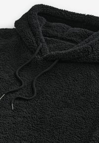 Sort fleece hættejakke med en tekstureret overflade, snoretræk og foret hætte. Stoffet virker blødt og varmt, ideelt til koldt vejr.