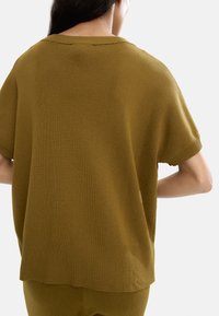 Przewymiarowany sweter z krótkim rękawem w kolorze mchu, z teksturą prążkowaną i ściągaczem, w luźnym kroju i szerokim dekolcie.