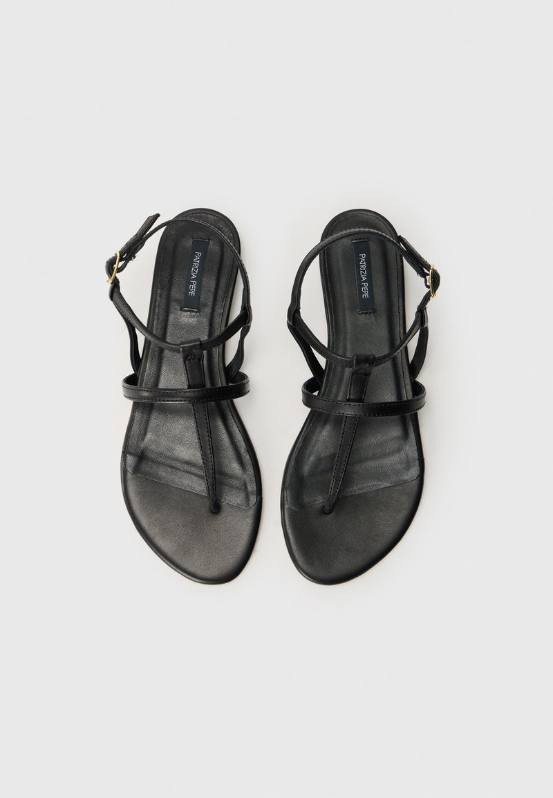 Sandali piatti neri realizzati in pelle liscia. Presentano sottili cinturini e una chiusura con fibbia. Soletta leggermente texturizzata e design a punta.