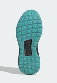 Semelle de chaussure avec un motif texturé, présentant une partie supérieure noire et une base en caoutchouc turquoise clair. Zone de soutien noire centrée.