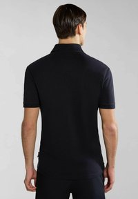 Musta poolo-paita, lyhyet hihat, ribattu kaulus, sileä pinta, slim fit. Tunnisteet näkyvät alareunassa. Paita on päällä miehellä, joka näkyy selkäpuolelta.