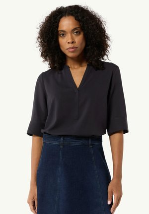Black, short-sleeve blouse with a V-neck and subtle stitching detail, paired with a dark denim skirt featuring a fitted waist and flared hem.