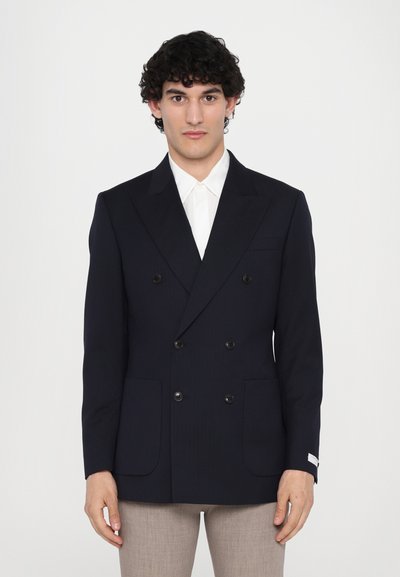 Blazer doppiopetto navy in tessuto fine, caratterizzato da due tasche frontali, bottoni neri e sottili righe verticali. Collo bianco sottostante.