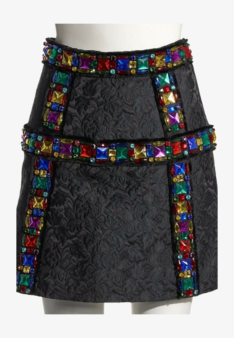Jupe noire texturée avec des bandes verticales et horizontales de grandes pierres précieuses carrées et ovales colorées en rouge, bleu, vert, violet et jaune.