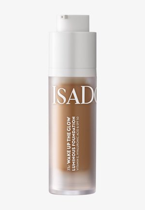 Flacon-pompe de fond de teint lumineux IsaDora Wake Up The Glow avec vitamine E, acide hyaluronique et SPF 50 en teinte beige moyen.