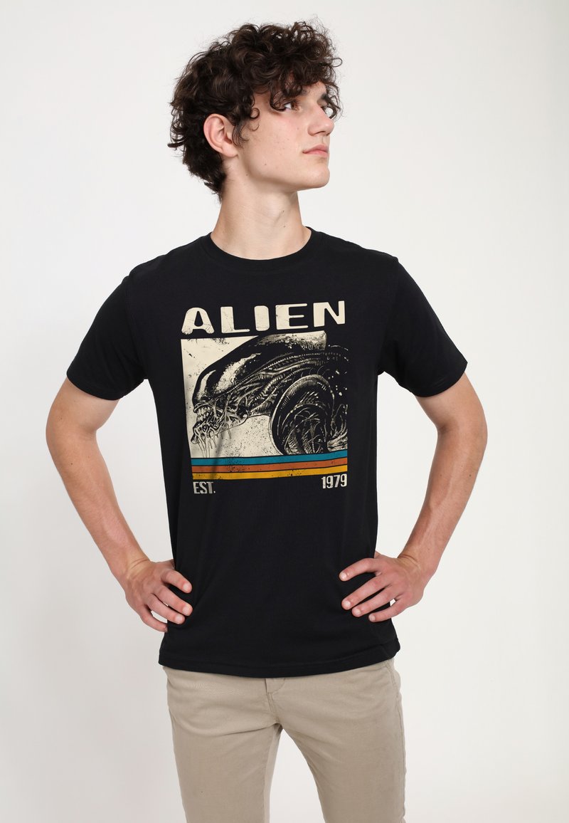 Czarna bawełniana koszulka z nadrukiem w stylu vintage przedstawiającym obcego stwora, kolorowe poziome paski oraz tekst "ALIEN EST. 1979."