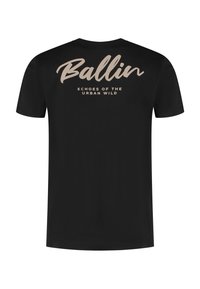 Zwarte t-shirt met korte mouwen, met "Ballin" in cursieve letters en "Echoes of the Urban Wild" eronder gedrukt in een contrasterende beige kleur.