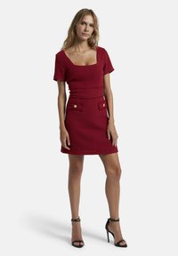 Rotes, ärmelloses Kleid mit quadratischem Ausschnitt und strukturiertem Stoff. Verfügt über eine taillierte Taille und zwei vordere Taschen mit dekorativen Knöpfen.