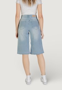 Culotte in denim azzurro chiaro con una vestibilità morbida, tasche posteriori e etichetta in vita. Indossate con sneakers alte bianche.