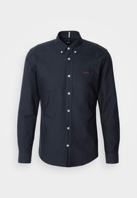 Chemise bleu marine foncé à manches longues avec boutons, col boutonné et petit logo "BOSS" brodé sur la poitrine gauche.