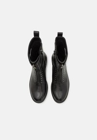 Paire de bottines en cuir noir avec fermetures éclair frontales et clous décoratifs, vues de dessus sur fond blanc.