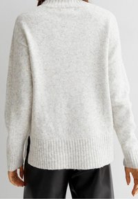 Hellgrauer, strukturierter Pullover mit geripptem Saum und hohem Kragen. Verfügt über seitliche Schlitze und besteht aus weichem Strickmaterial, das sich gut zum Schichten eignet.