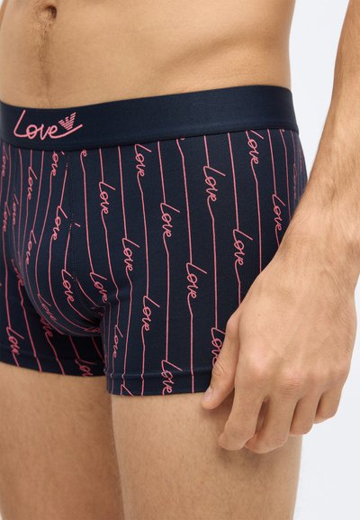 Tengerészkék boxer rövidnadrág testhezálló kialakítással, melyen rózsaszín, dőlt „love” felirat található függőleges csíkokon. Puha, rugalmas anyag elasztikus derékpánttal.