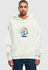 Cremefarbener Hoodie mit einer Vordertasche. Mit einem Druck eines Cartoon-Eiscreme-Charakters in Pastellfarben und dem Text: "Entspanne dich mit unseren cremigen Kreationen."