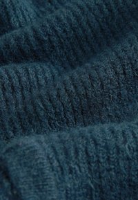 Tessuto lavorato a maglia blu scuro con una texture a coste, caratterizzato da morbidi e pelosi filamenti che creano un aspetto accogliente.
