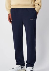 Marinefarbene Jogginghosen aus weichem Stoff mit einem elastischen Bund. Sie verfügen über ein kleines weißes und rotes Logo auf dem oberen linken Oberschenkel.