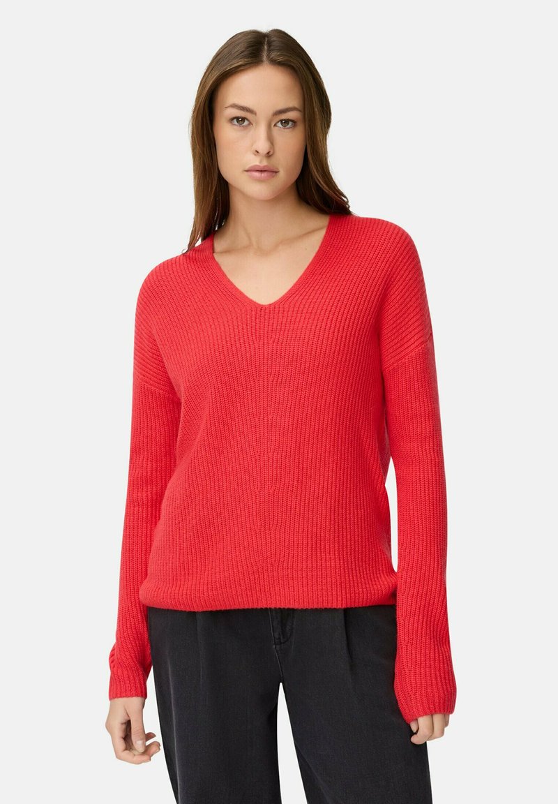 Roter, gerippter Strickpullover mit V-Ausschnitt und langen Ärmeln. Hat eine lockere Passform und eine strukturierte Oberfläche. Kombiniert mit schwarzen Hosen.