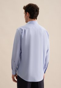 Camicia azzurra a maniche lunghe con colletto button-down, caratterizzata da una texture liscia, orlo curvo e polsini abbottonati sulle maniche.