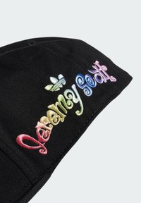 Svart keps med flerfärgad broderad text "Jeremy Scott" och en liten logotyp. Tillverkad av bomull med en jämn textur.