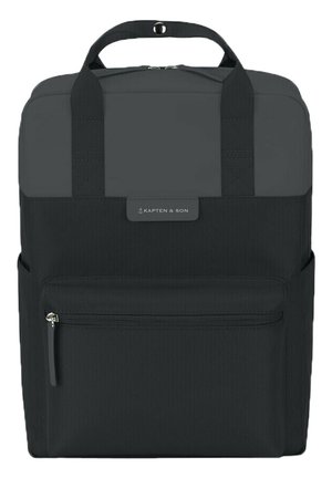 Sac à dos noir rectangulaire avec poignées sur le dessus, poche avant zippée, et étiquette logo "Kapten & Son" centrée au-dessus de la poche.