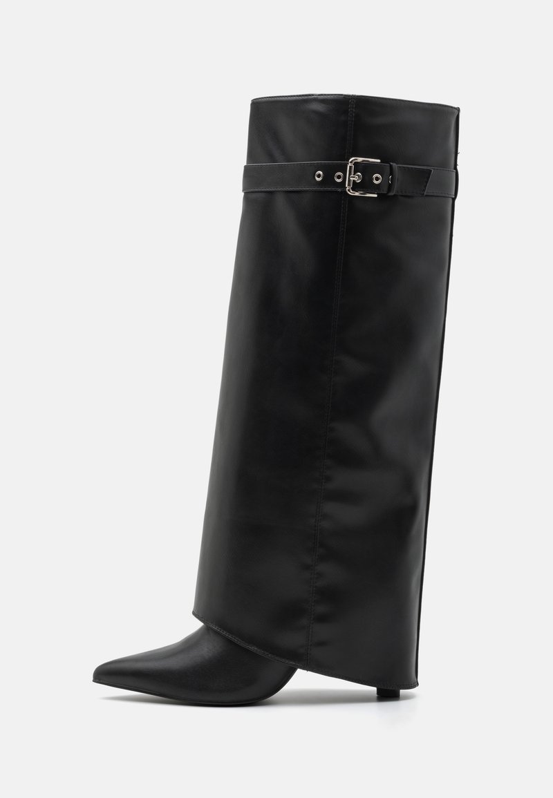 Botte haute en cuir noir avec bout pointu et une sangle avec boucle argentée autour du haut du mollet sur fond blanc.