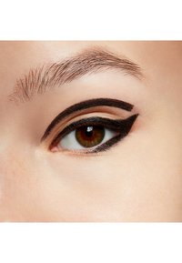 Close-up van een oog met gedurfde zwarte eyeliner, in een cat-eye stijl. De huid heeft een lichte textuur en natuurlijke tinten met zichtbare wimpers.