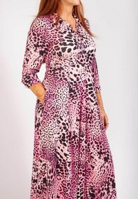 Lång klänning med ett rosa och svart leopardmönster, knappstängning fram och långa ärmar med manschetter. Tyget verkar slätt och lätt.