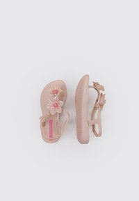 Sandalias de goma rosas con acentos florales, que presentan dos flores grandes y una correa, plantillas texturizadas y suela lisa.
