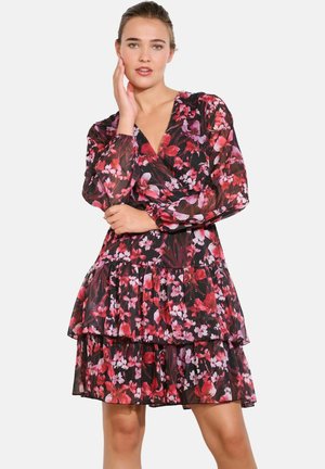 Robe à volants florale avec un fond sombre et des fleurs rouges et roses, manches longues en voile et décolleté en V profond. Tissu léger.