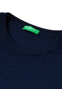 Col rond en tricot bleu marine avec un col côtelé et une étiquette verte "United Colors of Benetton" cousue à l'intérieur.