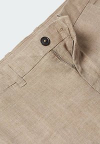 Béžové lněné kalhoty s zipovým zapínáním a knoflíkovým uzávěrem, s poutky na opasek a hladkou texturou. Detailní pohled na lem.