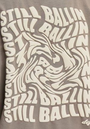 Neutral beige fabric featuring swirling white 3D text that reads "STILL BALLIN'" in various orientations and sizes across the surface.