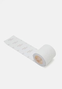 Balta mežģīņu līmplēve sarullēta, ar ziedu rakstu, izpušķotu tekstūru un atkārtotu "#dreamMAGIC" tekstu uz bēša fona.