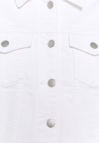 Witte denimjack met zilveren drukknoopjes, twee voorzakken en een klassieke kraag. De stof heeft een gladde, structuur afgewerkte uitstraling.