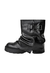 Zwarte leren enkelboot met een slouch-ontwerp, vierkante neus en een zijgesp. Dikke zool biedt extra hoogte en stabiliteit.