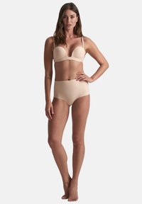 Beige lingerieset met een gepadded bh met een diepe decolletélijn en bijpassende high-waisted slip, vervaardigd van een gladde, rekbare stof.