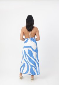 Maxi dress con un motivo a onde blu e bianche, realizzata in tessuto leggero, con dettaglio di laccio sul retro e design della schiena scoperta.