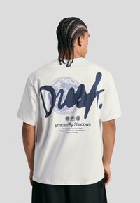 White cotton t-shirt featuring a large navy blue graphic on the back, including text and a moon design. Short sleeves, relaxed fit.