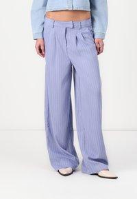 Ανοιχτό μωβ παντελόνια φαρδιάς γραμμής με λευκές λεπτές ρίγες, που διαθέτουν πιέτες και λεία υφή. Συνδυασμένα με μπεζ μυτερές γόβες.