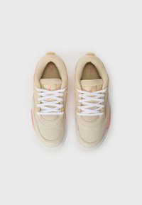Zapatillas beige con cordones blancos, parte superior de malla texturizada y cuero suave, con un acento coral y un logotipo en la lengüeta.