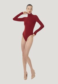 Röd långärmad bodysuit med hög hals. Slät, elastisk tyg; åtsittande design framhäver siluetten. Bärs med beiga högklackade skor.