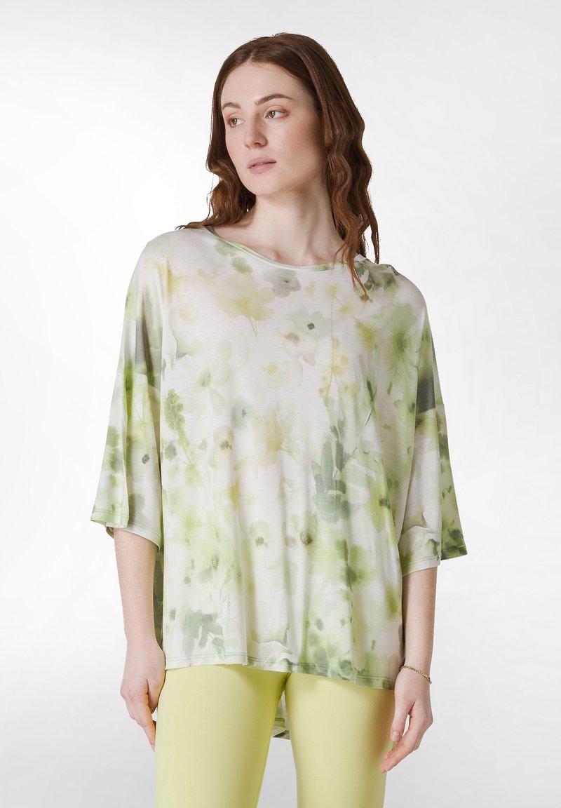 Lätt, löst sittande topp i mjukt tyg. Har en blommig design i gröna och gula nyanser, med batwingärmar och en böjd fåll.