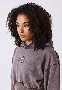Sudadera gris heather hecha de un tejido suave con un corte holgado. Presenta un logo frontal y capucha con cordón; texturizada para mayor dimensión.