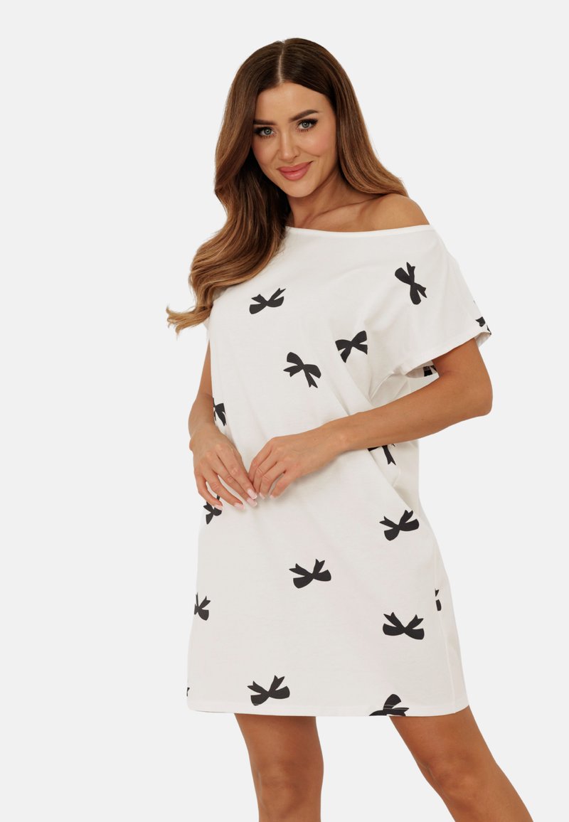 Biała bawełniana sukienka z czarnymi wzorami w kokardy, luźny fason, z odkrytymi ramionami, krótkie rękawy i długość do kolan.