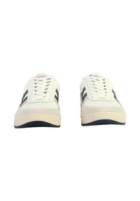 Baskets blanches avec des accents en daim, présentant des rayures sombres, une pointe arrondie et une semelle en caoutchouc texturée. Les lacets sont visibles et bien enfilés.