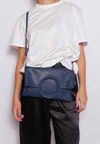 Borsa a tracolla in pelle blu navy con un dettaglio a pattina arrotondata e superficie texture. Presenta una cintura rimovibile e un design elegante.